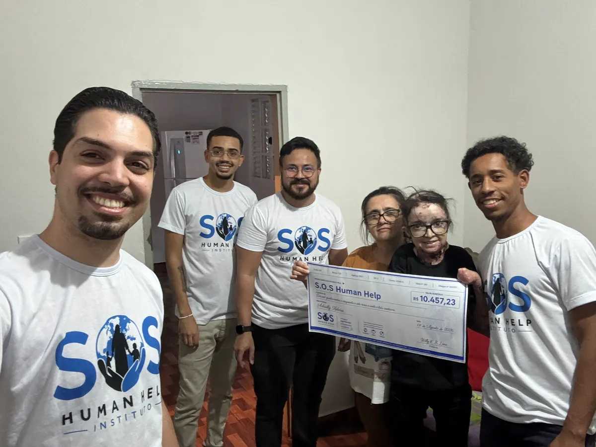 Equipe do SOS Human Help entregando o valor arrecadado em uma campanha solidária