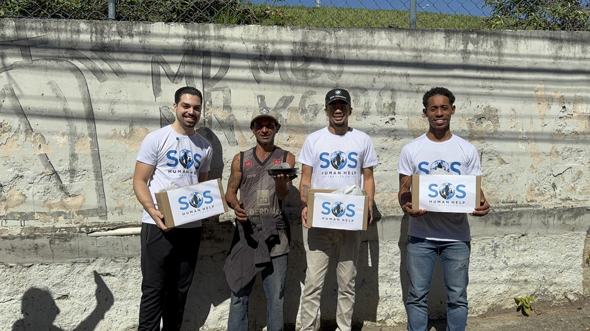 Voluntários do SOS Human Help entregando caixas de doação e marmita para um morador de rua