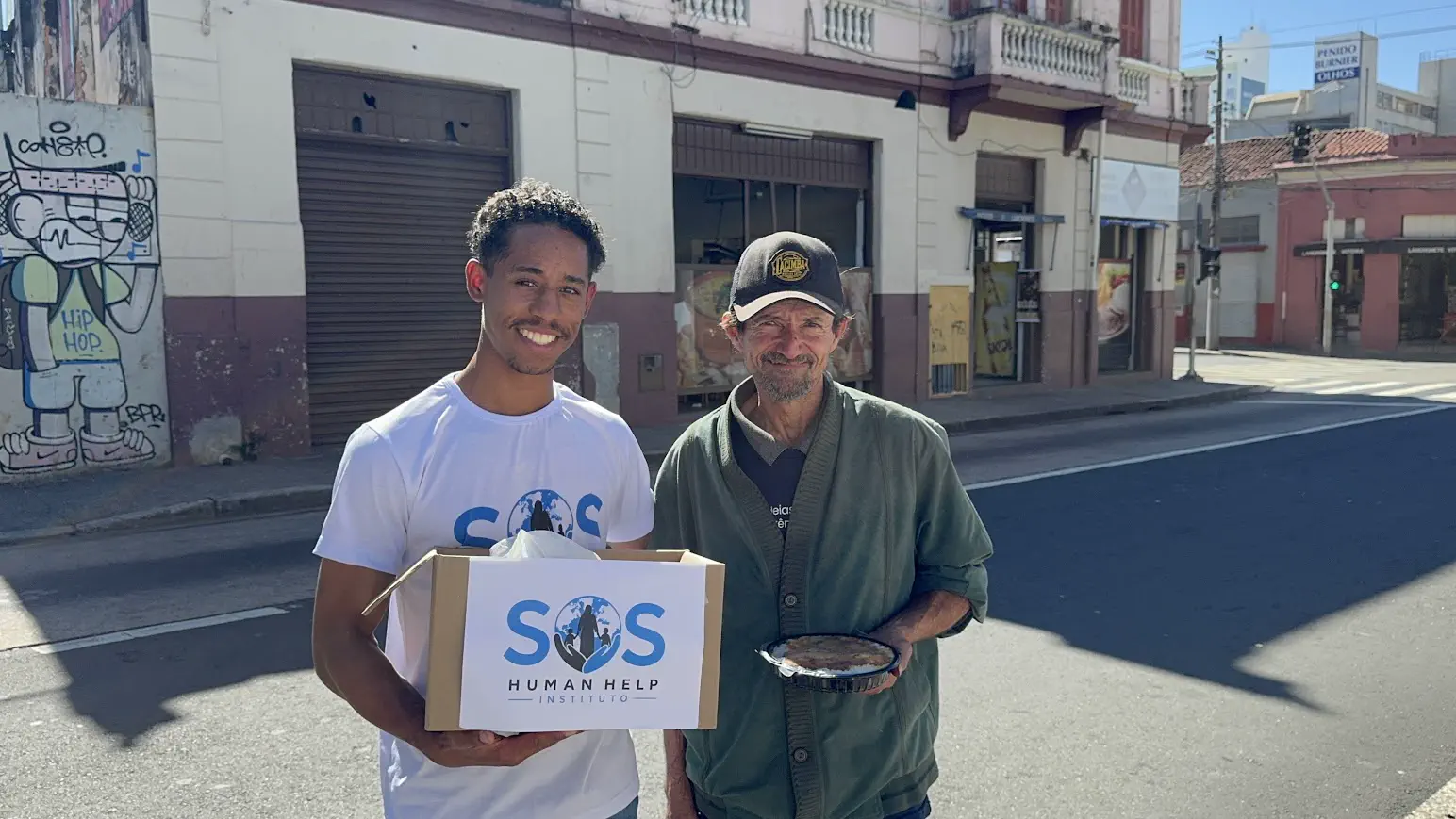 Voluntário da SOS Human Help entregando marmita a morador de rua