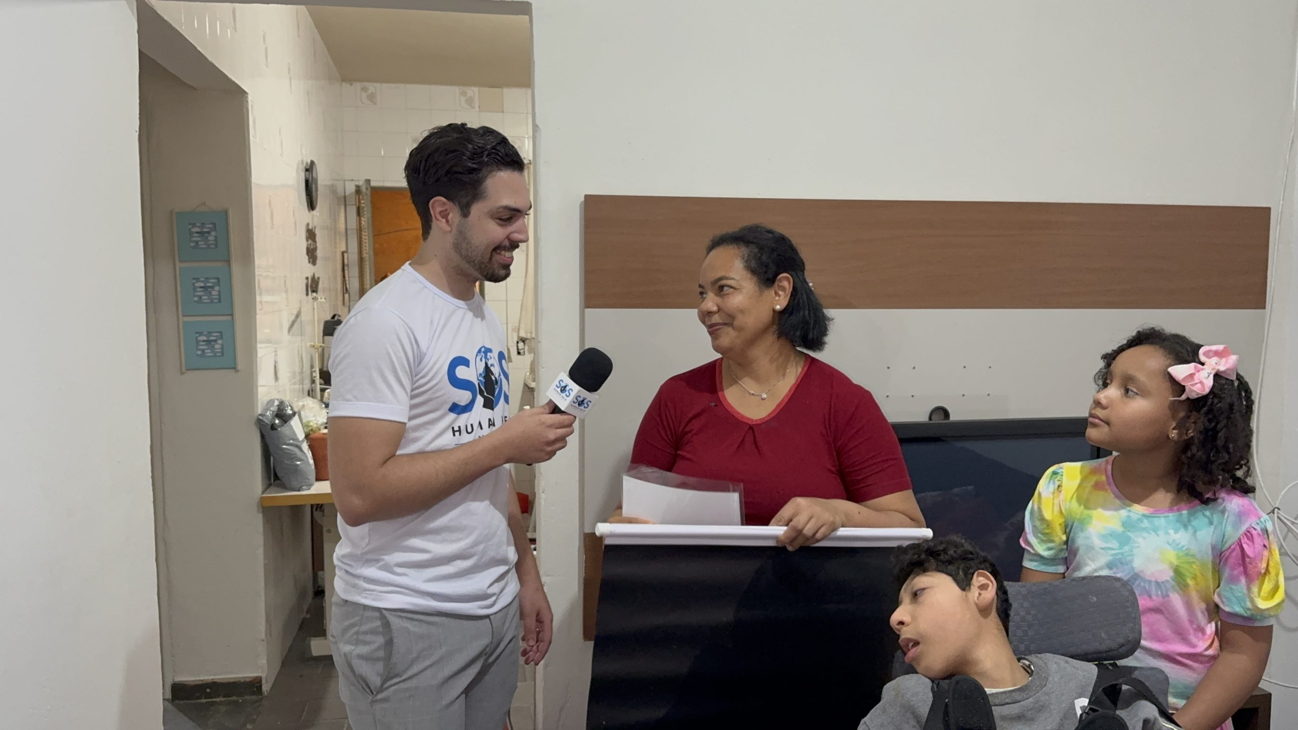 Volunt&aacute;rio do SOS Human Help entrevistando a m&atilde;e da fam&iacute;lia atendida, com os filhos ao lado