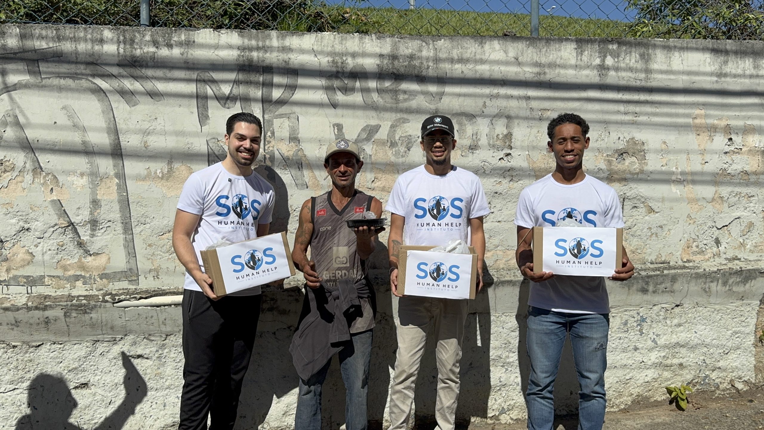 Volunt&aacute;rios do SOS Human Help entregando caixas de doa&ccedil;&atilde;o e marmita para um morador de rua